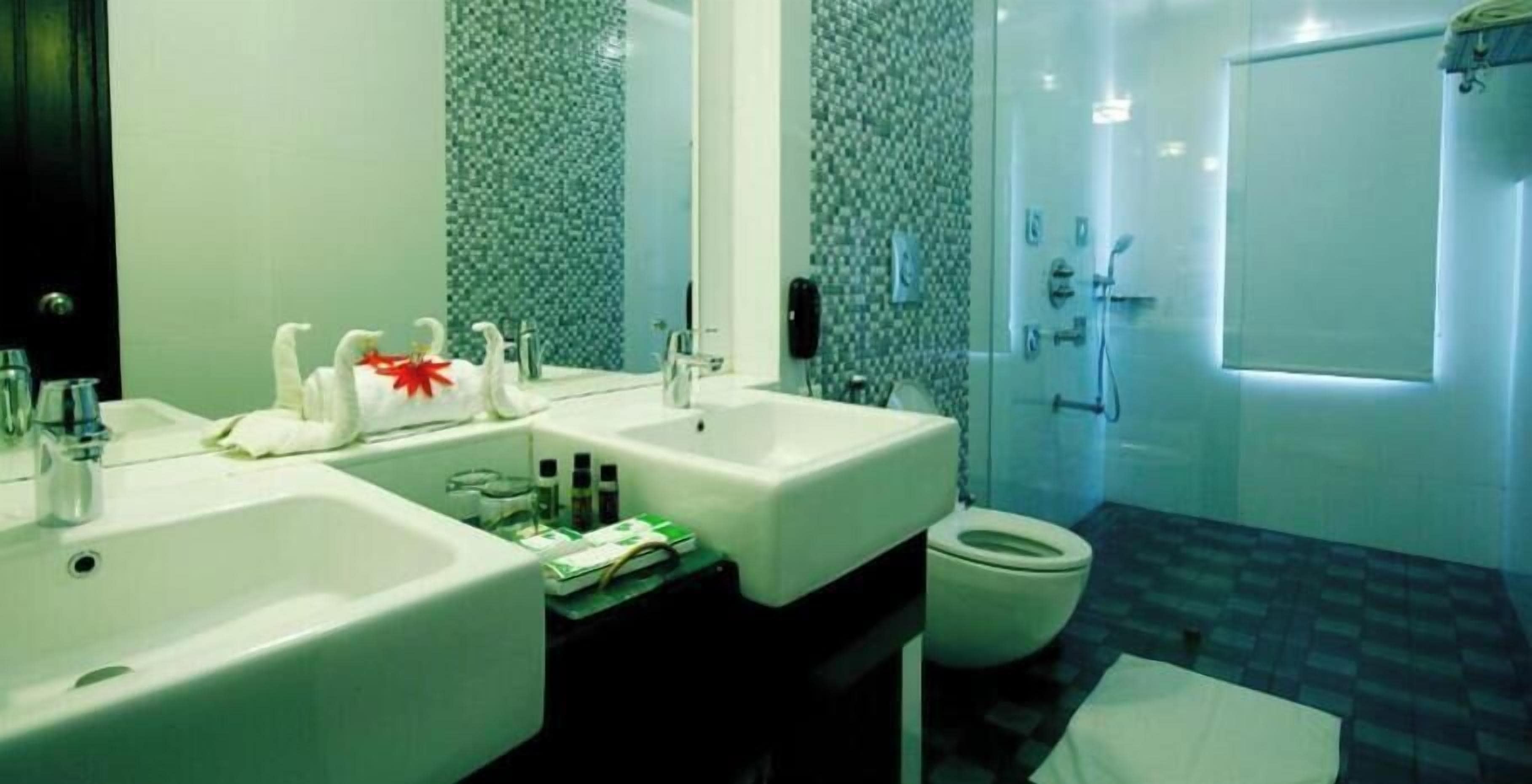 Un baño con dos lavamanos, un inodoro y una zona de ducha.