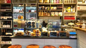 A bakery counter with various baked goods, a refrigerator with meat products, and shelves stocked with condiments and beverages.