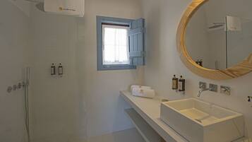 Une salle de bain moderne avec une douche à l’italienne, un grand miroir et un lavabo blanc.