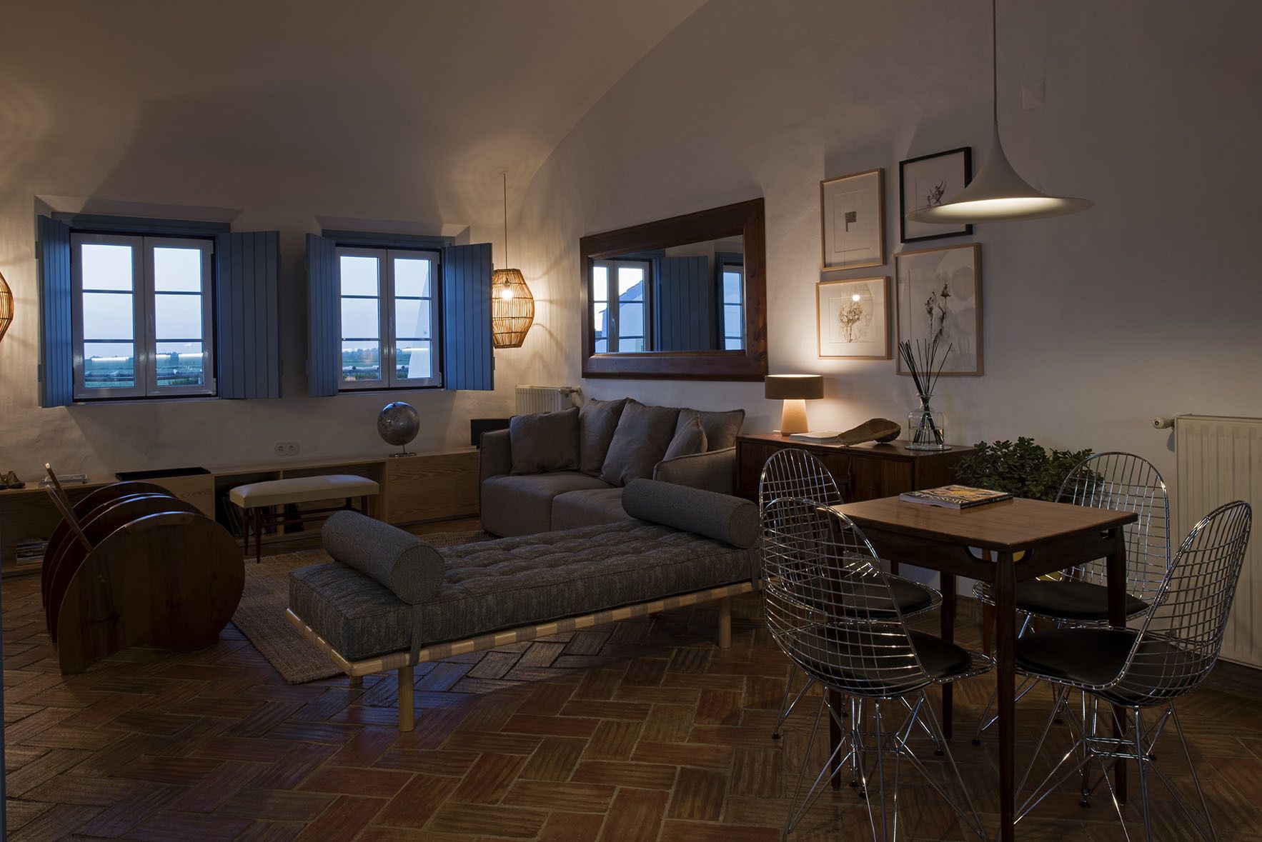 A cozy living room with a sofa, dining table, chairs, and a piano.