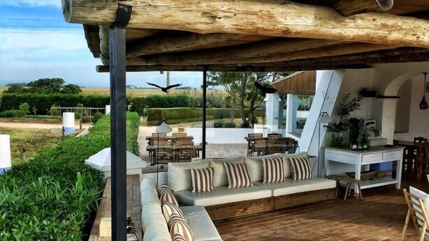 An outdoor patio with a wooden pergola, a sofa set, dining area, and a kitchen area. - Herdade Do Touril (Odemira)