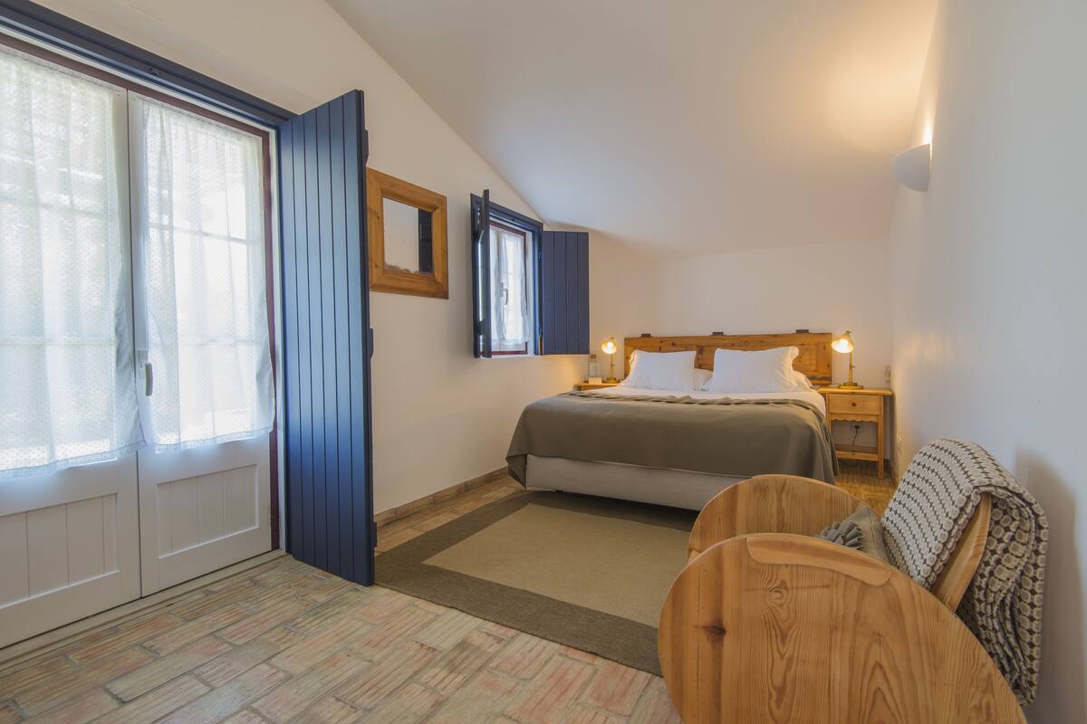A bedroom with a bed, bedside tables, a mirror, and a window with curtains.