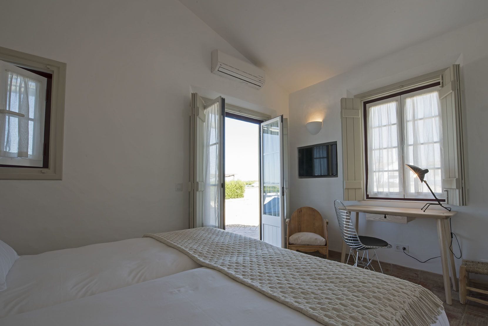 A bedroom with a bed, a desk, a chair, and a window.