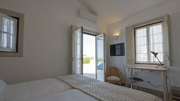 A bedroom with a bed, a desk, a chair, and a window.