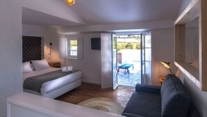 A bedroom with a bed, a sofa, a lamp, and a view of the outdoors. - Herdade Do Touril (Odemira)