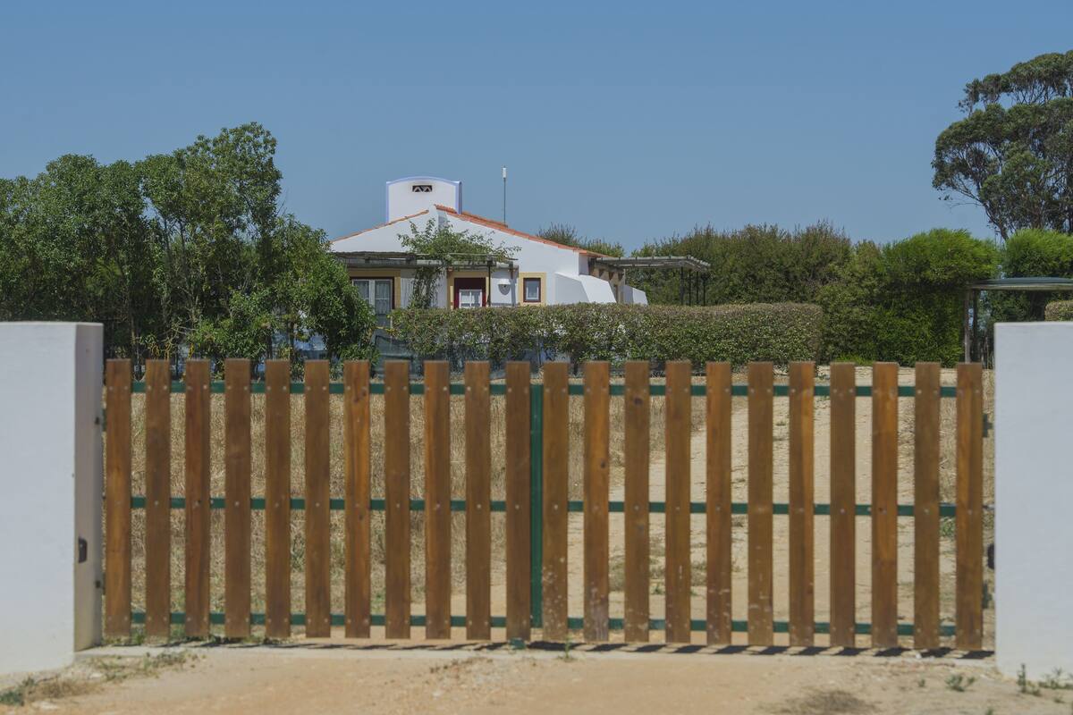 A gated property with a white building, a red roof, and a green fence.