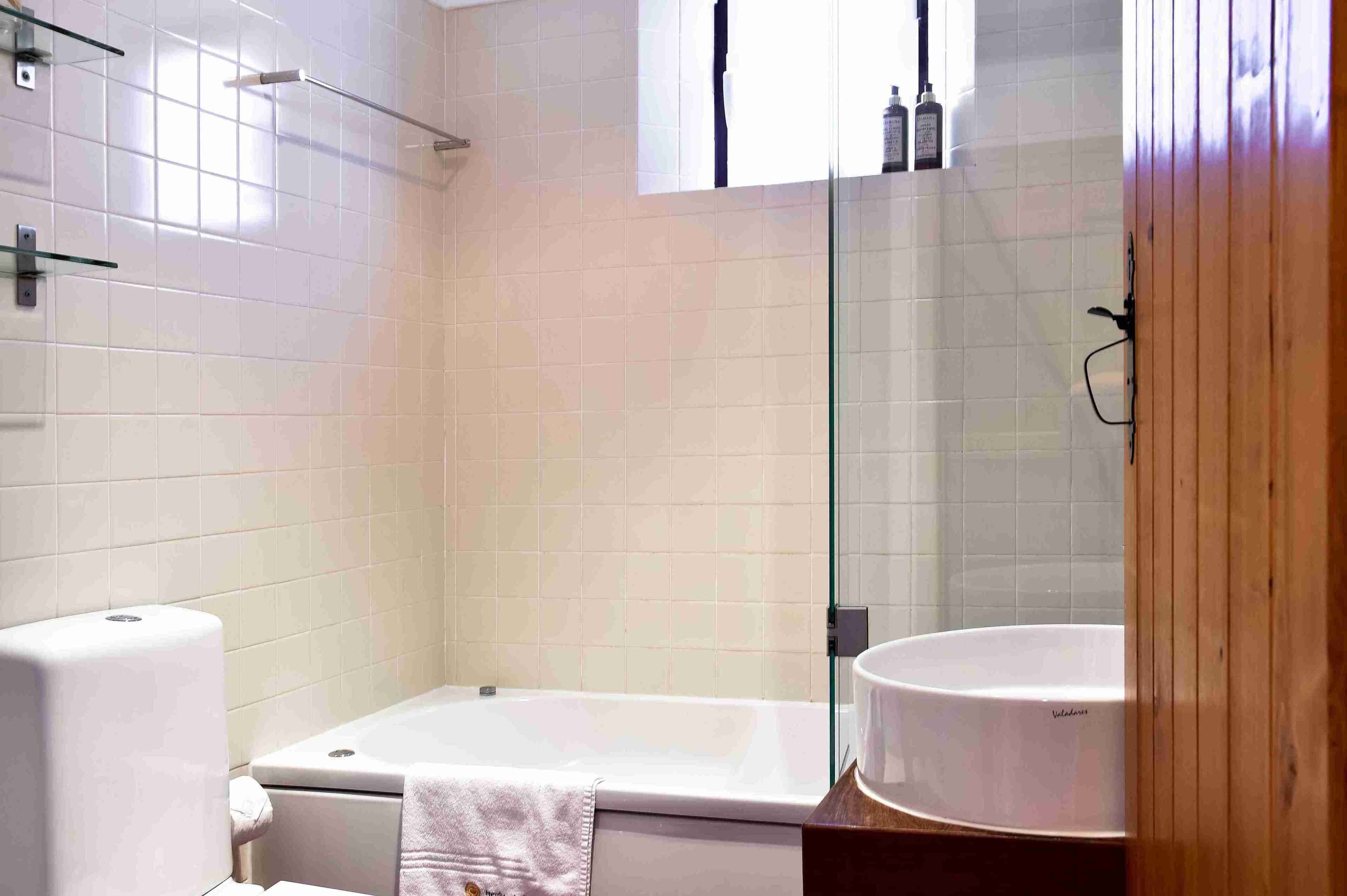 Une salle de bain moderne équipée d’une baignoire, de toilettes, d’une douche à parois de verre et d’un lavabo.