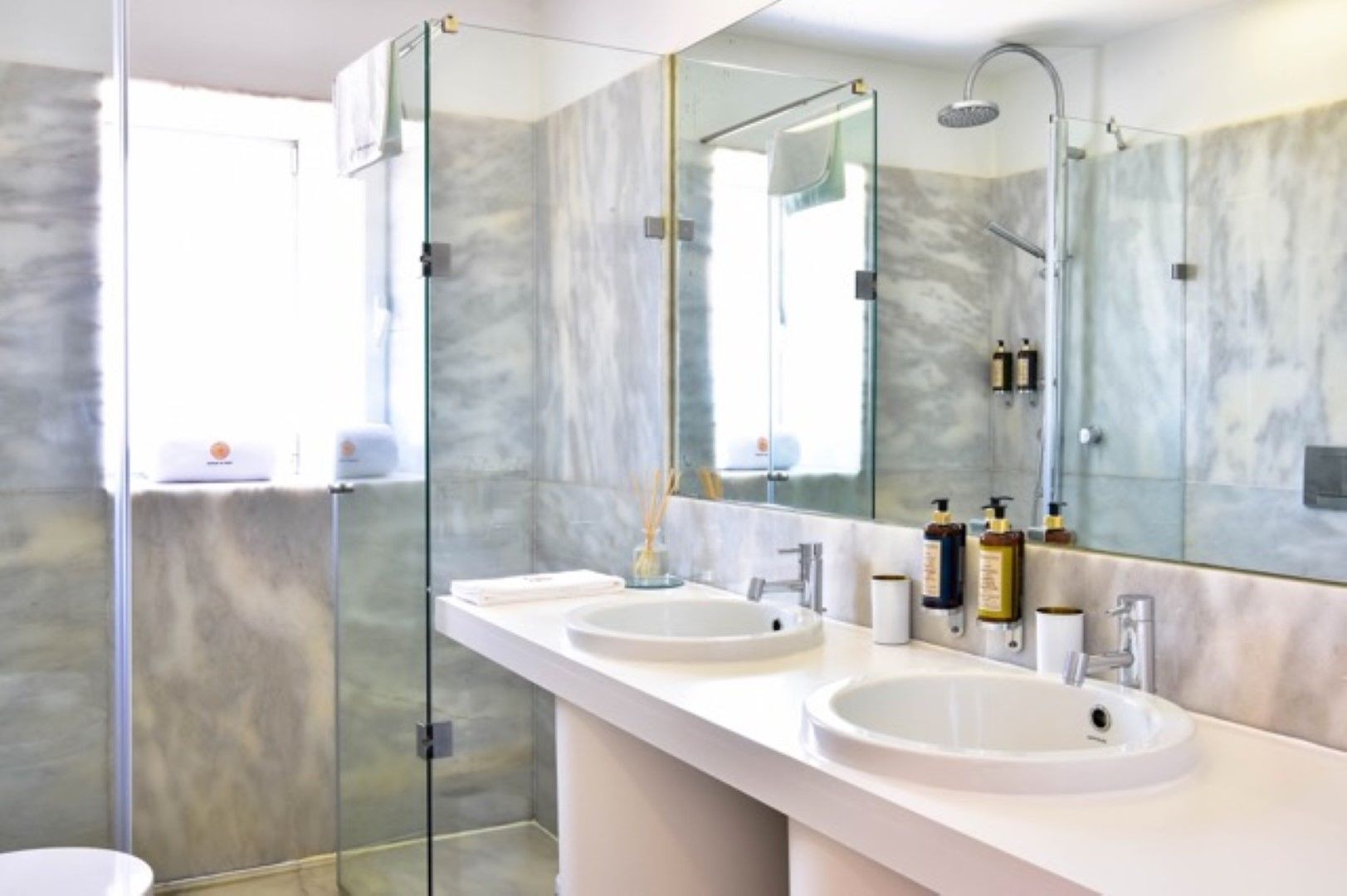 A modern bathroom with two sinks, a glass shower enclosure, and a large mirror.