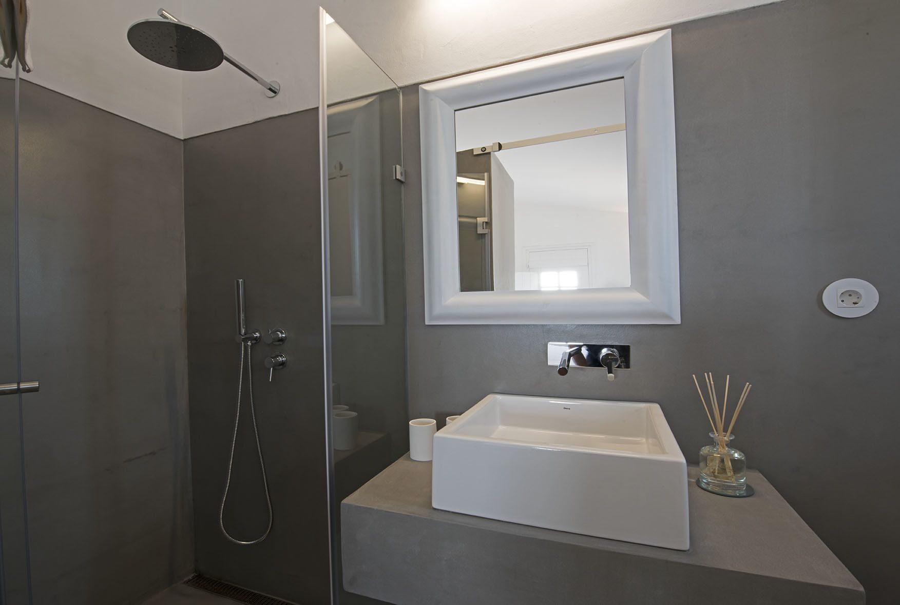 Une salle de bain moderne avec une douche à parois de verre, un lavabo blanc et un miroir au-dessus.