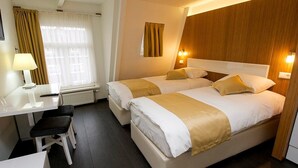 A hotel room with two beds, a desk, and a chair.