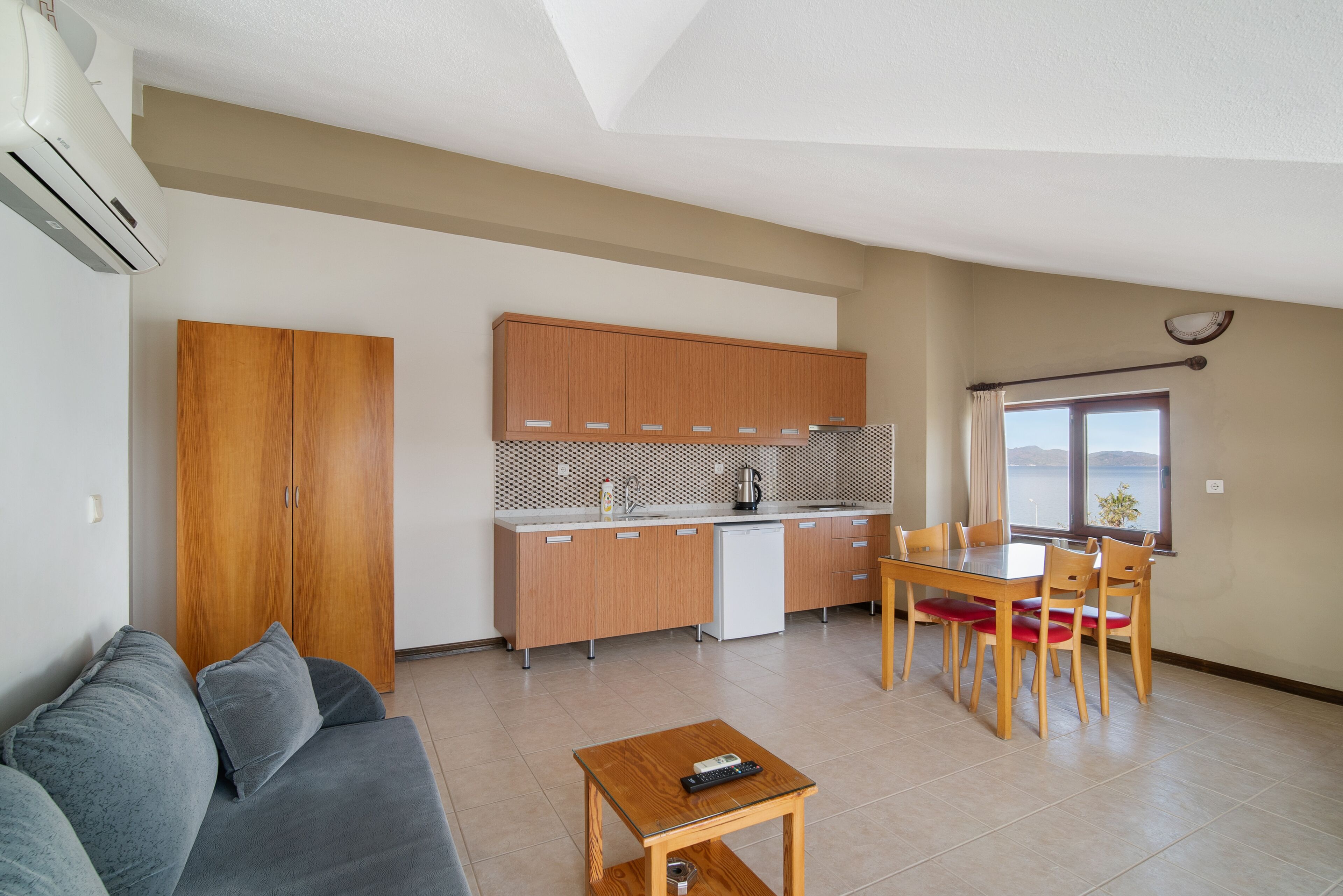 A compact living space with a kitchenette, a dining area, a sofa, and a view of the outdoors.