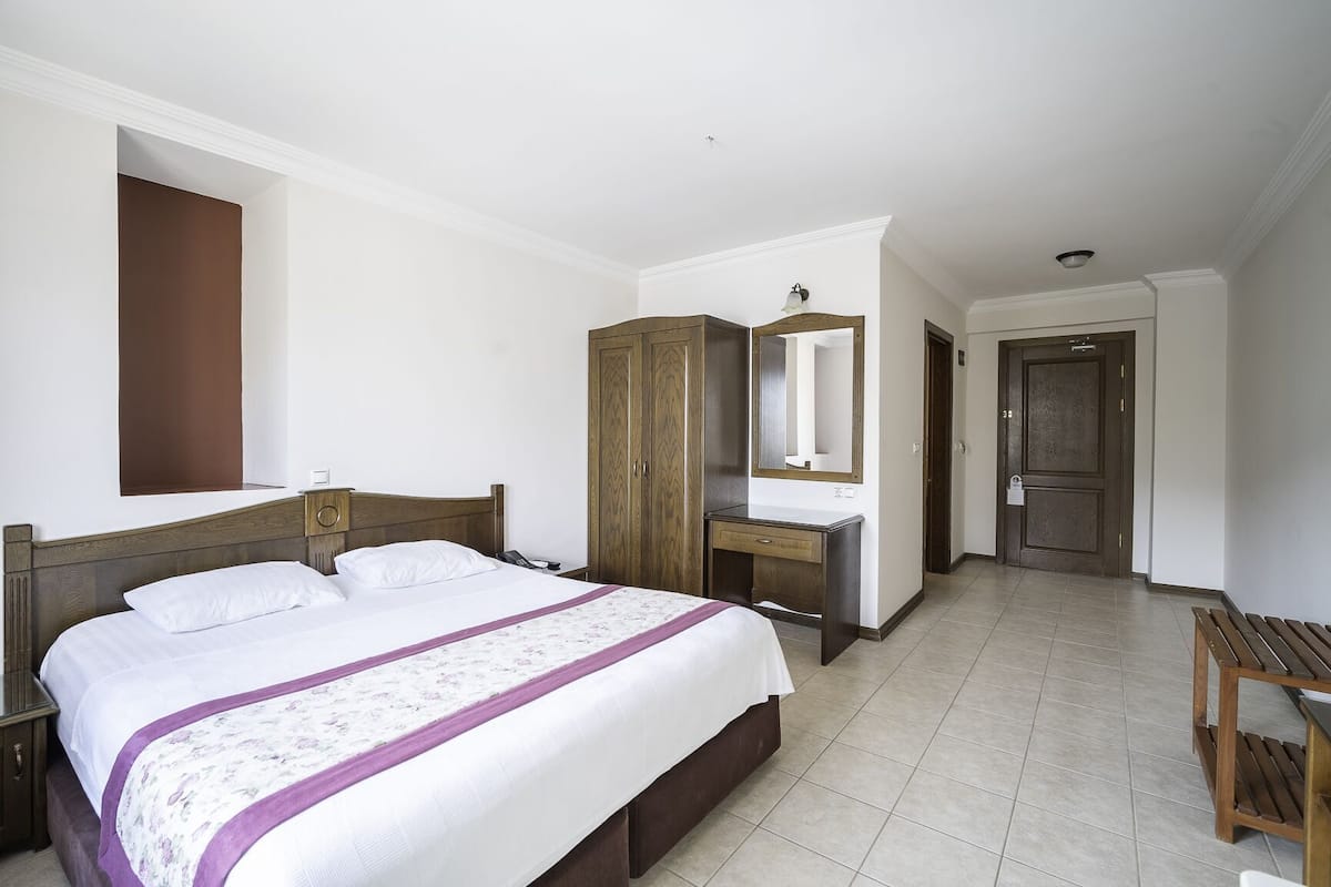 Une chambre à coucher avec un lit, une armoire en bois, un petit bureau et un banc.
