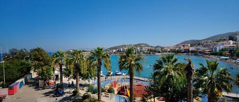 A coastal town with a marina, palm trees, and a clear blue sky.