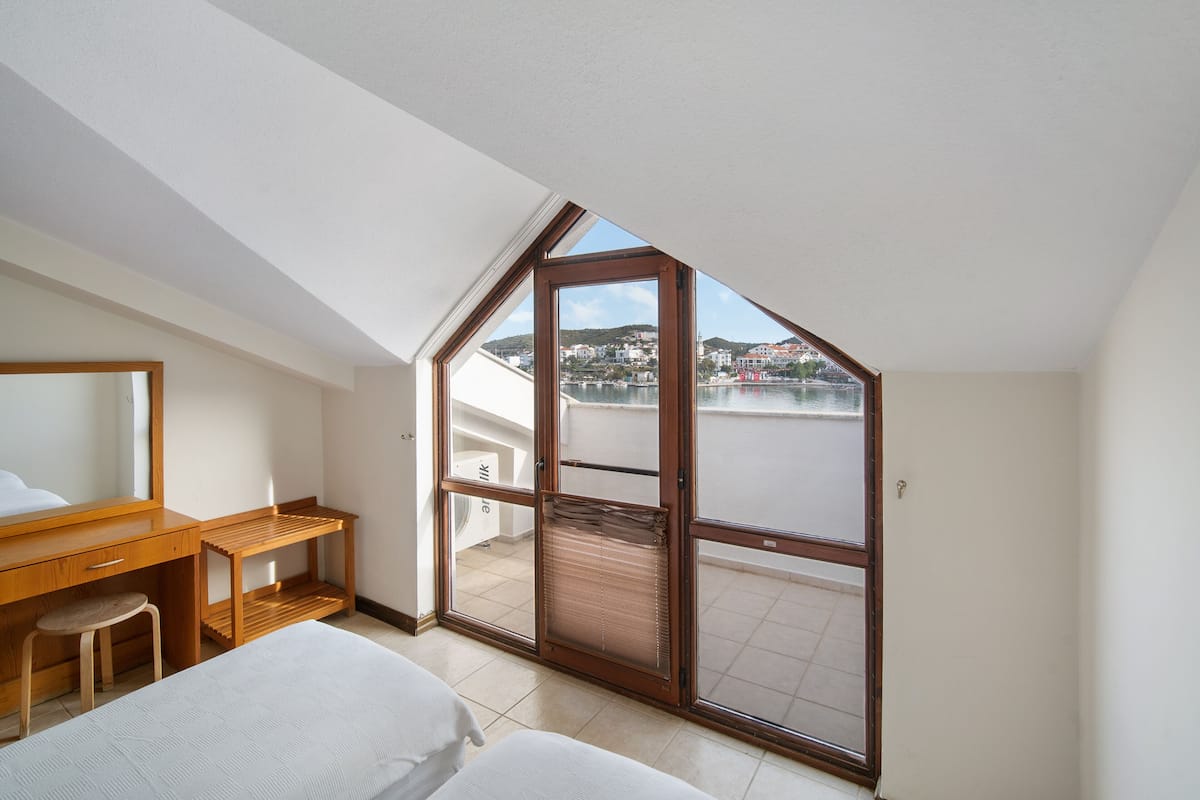 Une chambre avec une grande fenêtre, un bureau et un lit.