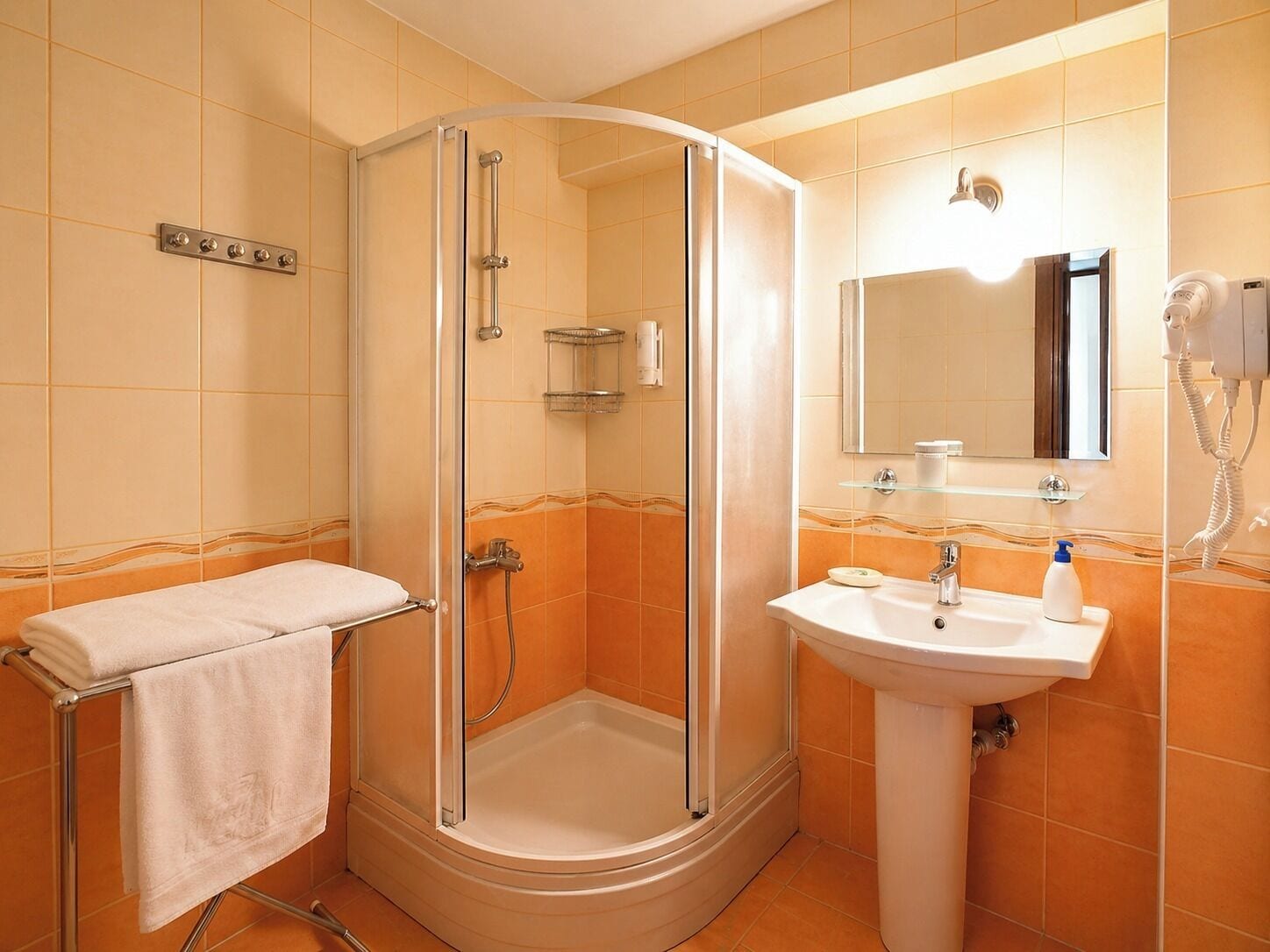 A bathroom with a glass-enclosed shower, a sink with a mirror, and a towel rack.