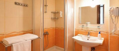 A bathroom with a glass-enclosed shower, a sink with a mirror, and a towel rack.