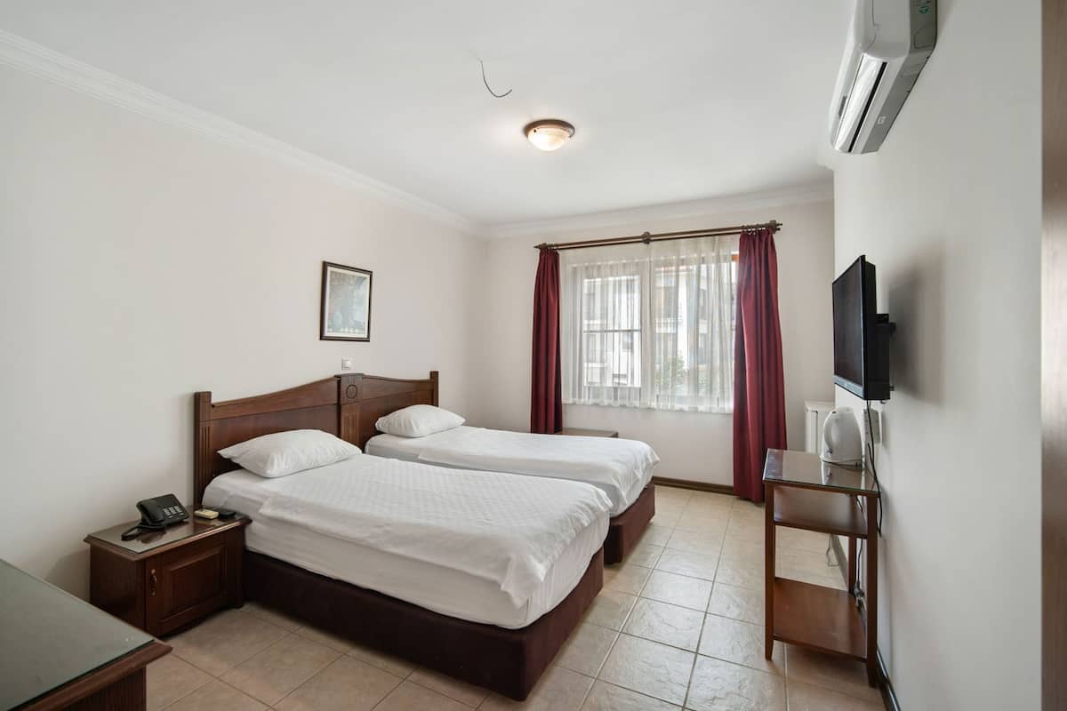 Une chambre d’hôtel avec deux lits, un bureau, un téléphone, une télévision et un appareil de climatisation.