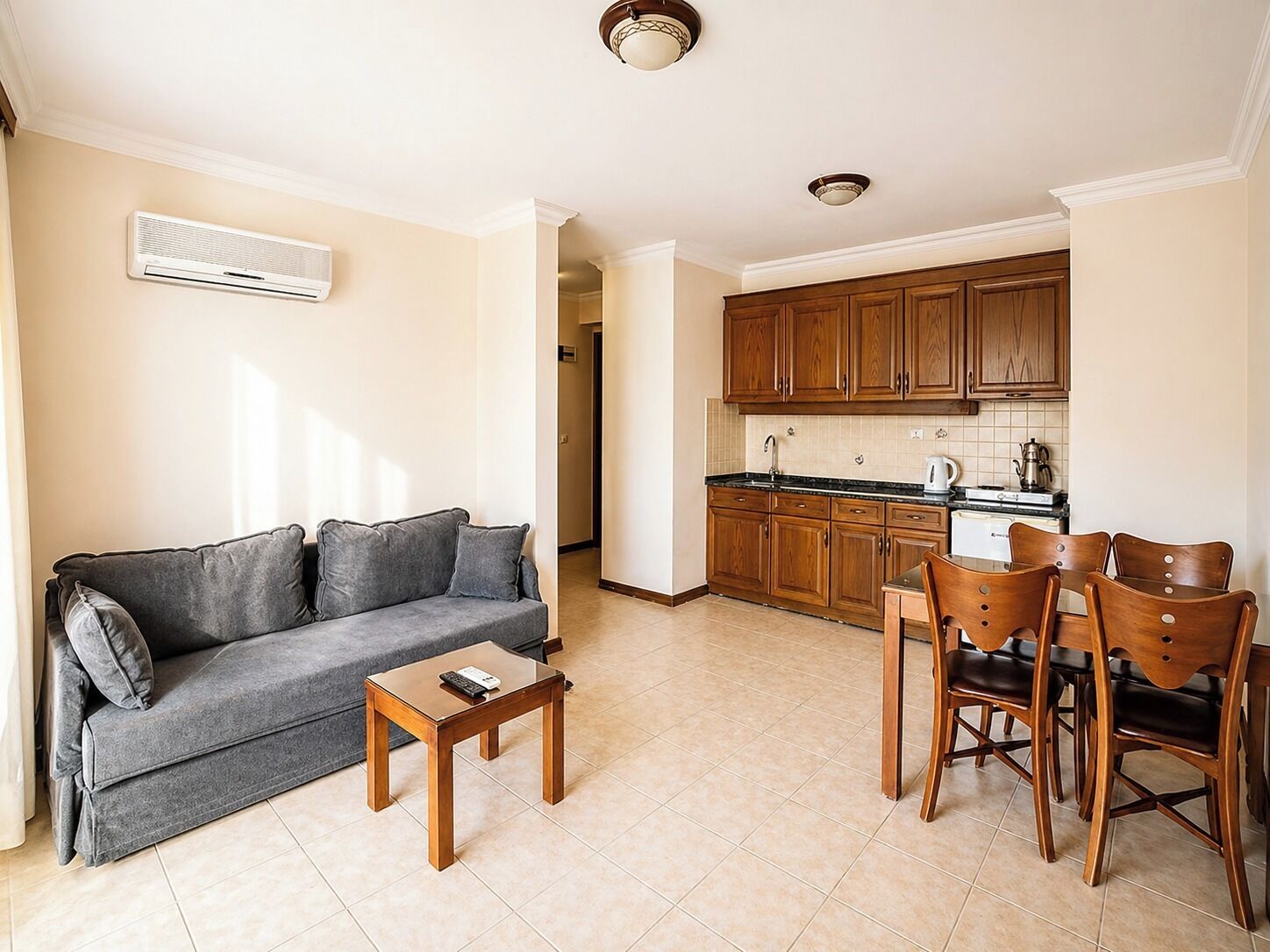 Una sala de estar con un sofá, una mesa de centro y un comedor con sillas de madera, con una cocina al fondo.