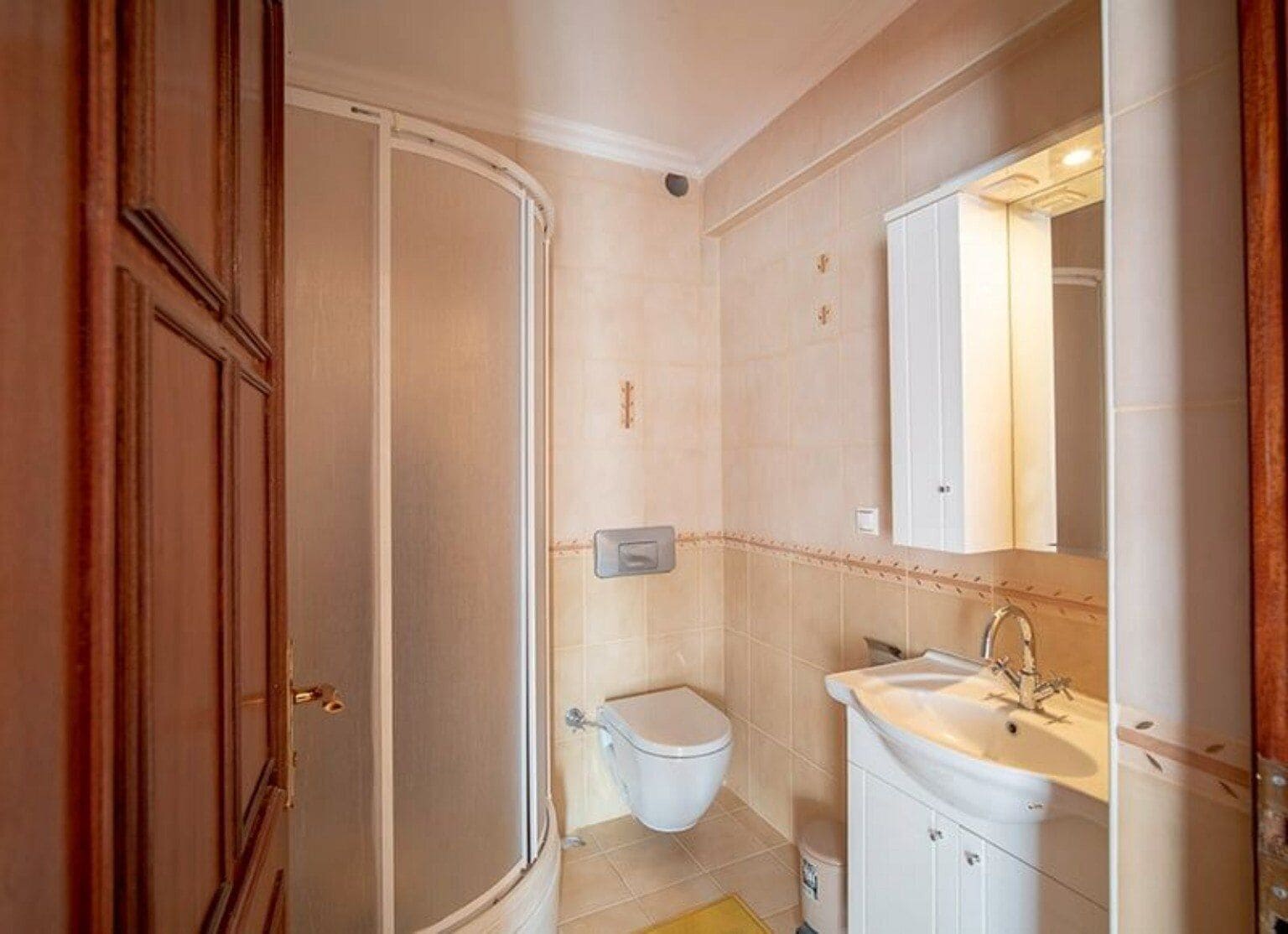 A bathroom with a toilet, sink, and mirror.