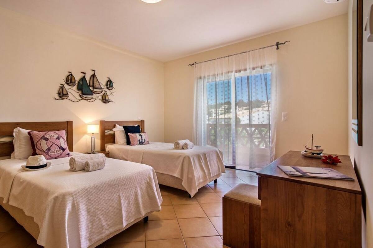 Una habitación con dos camas, un escritorio y ventana con vistas.