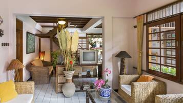 A cozy living room with wicker furniture, a television, and decorative plants.