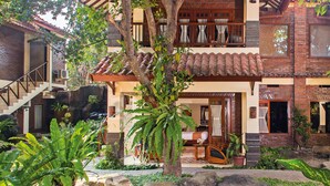 A traditional house with a tiled roof, a stone staircase, and a small pond with fish. - Duta Garden Hotel (Yogyakarta)