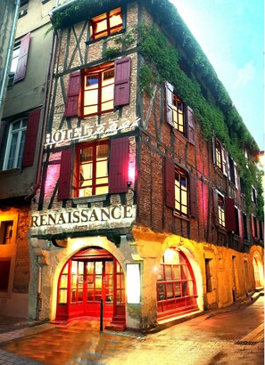 A Renaissance hotel with a stone facade, red shutters, and a sign above the entrance.