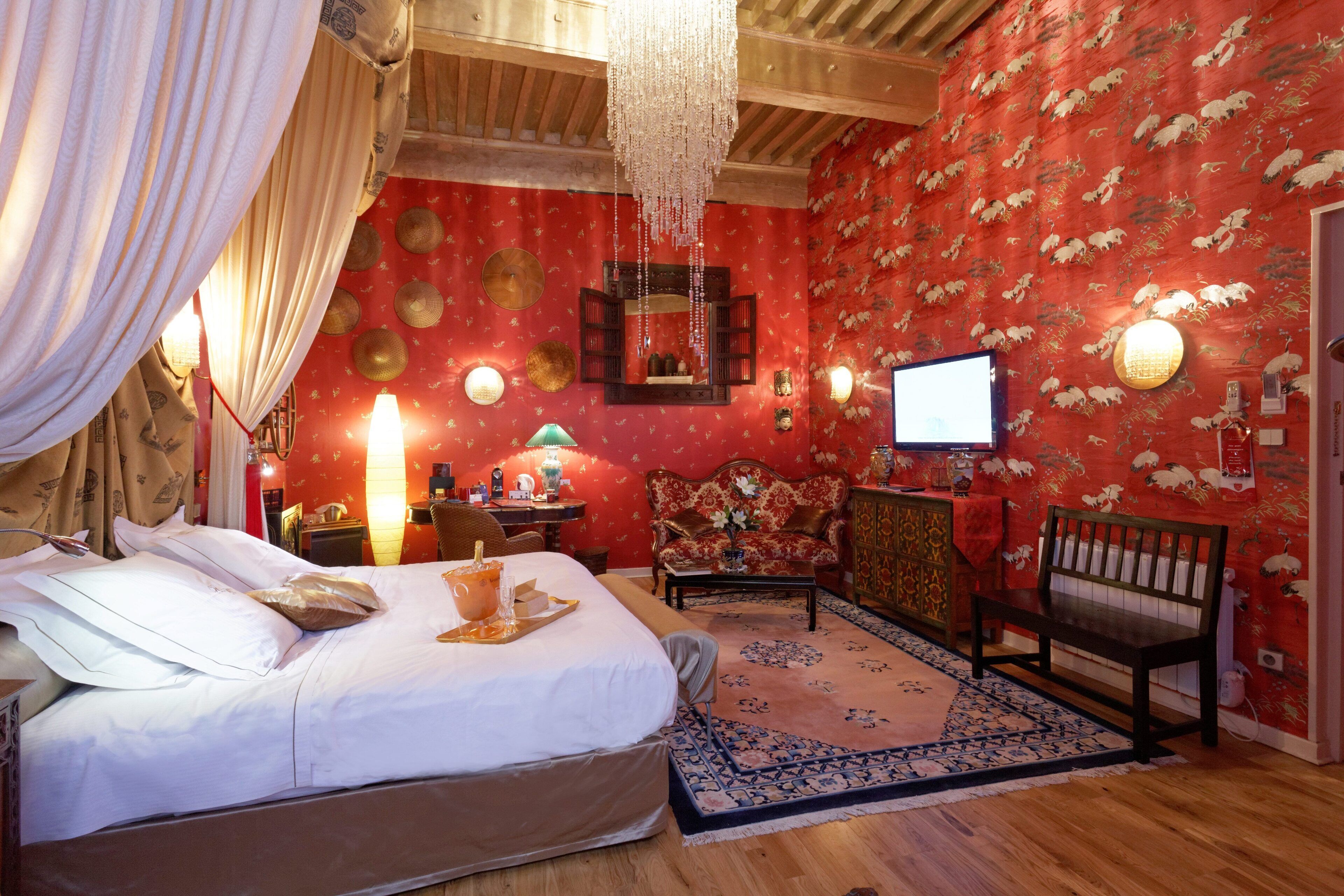 A room with a bed, a desk, a chair, a bench, a mirror, and a television.