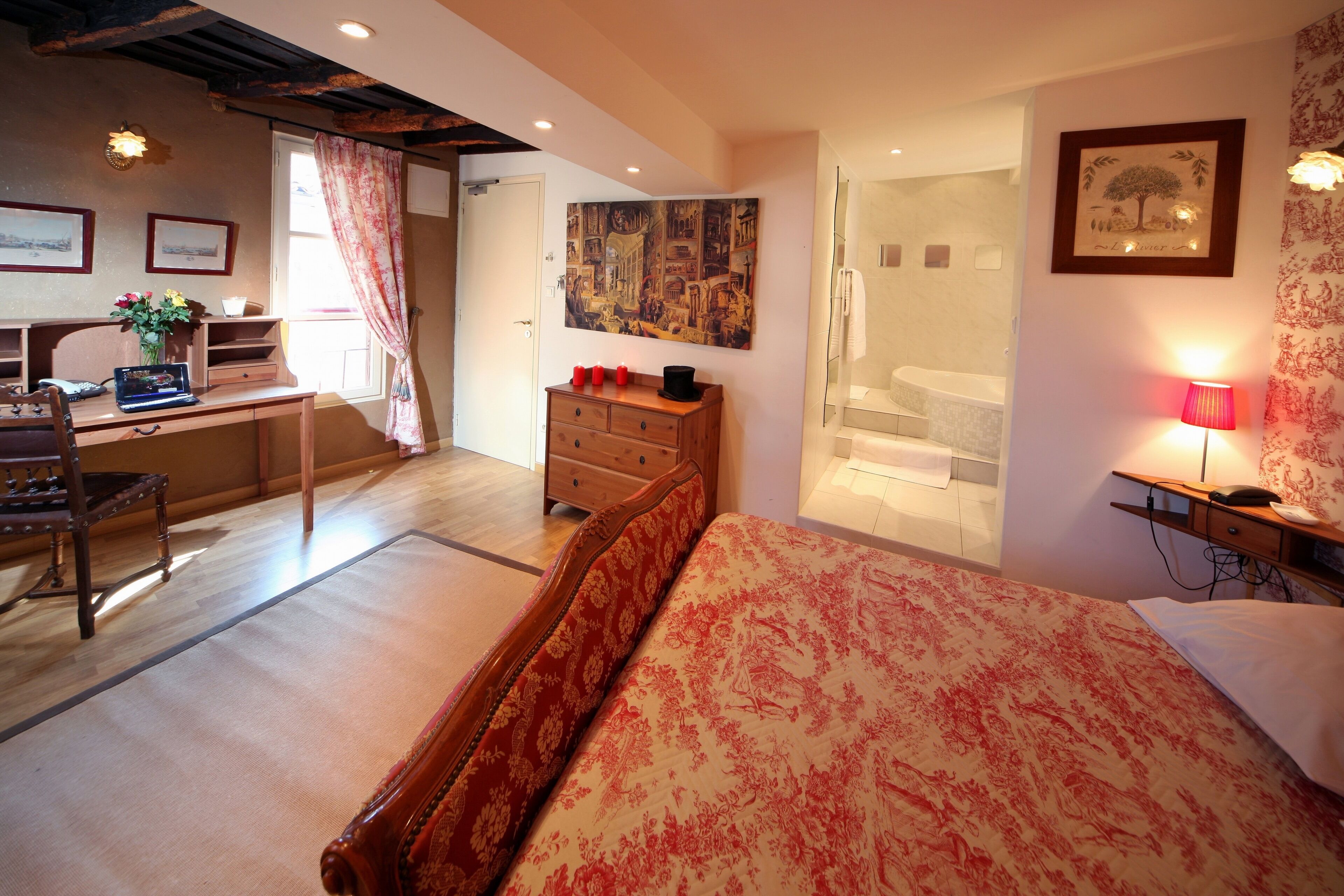 Un dormitorio con cama, escritorio, cómoda y baño visible a través de una puerta abierta.
