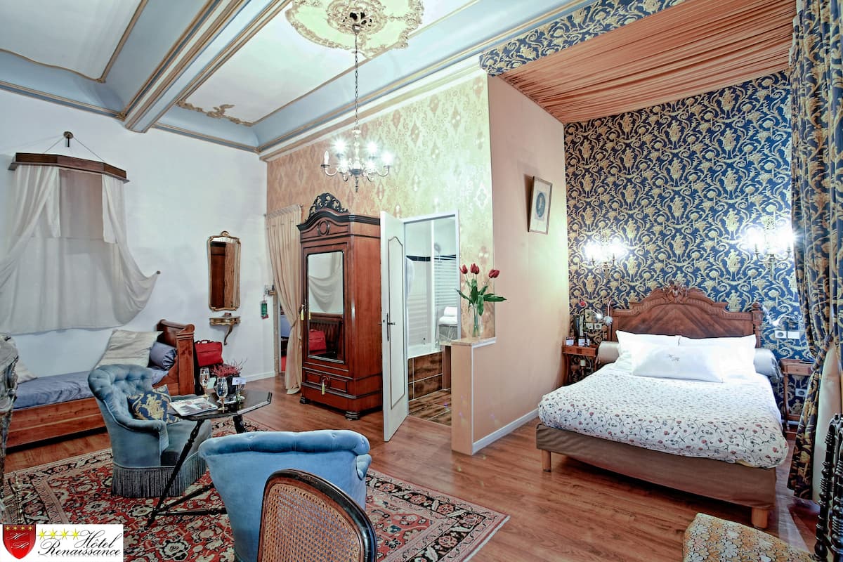 A bedroom with a bed, a chair, a vanity, and a wardrobe.