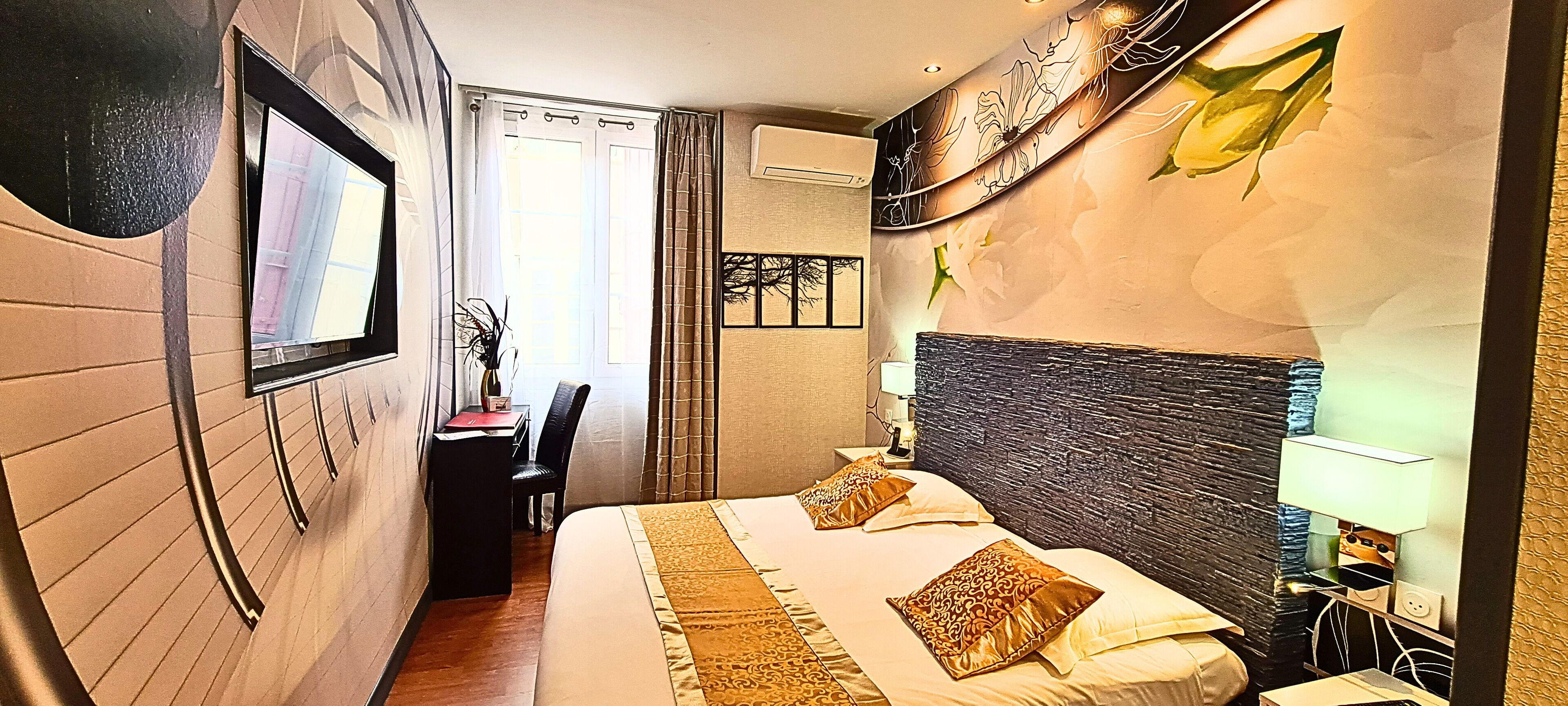 Une chambre d’hôtel avec un lit, un bureau, une chaise et une fenêtre avec des rideaux.
