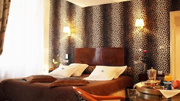 A hotel room with a bed, a nightstand, a lamp, and a table with breakfast items.