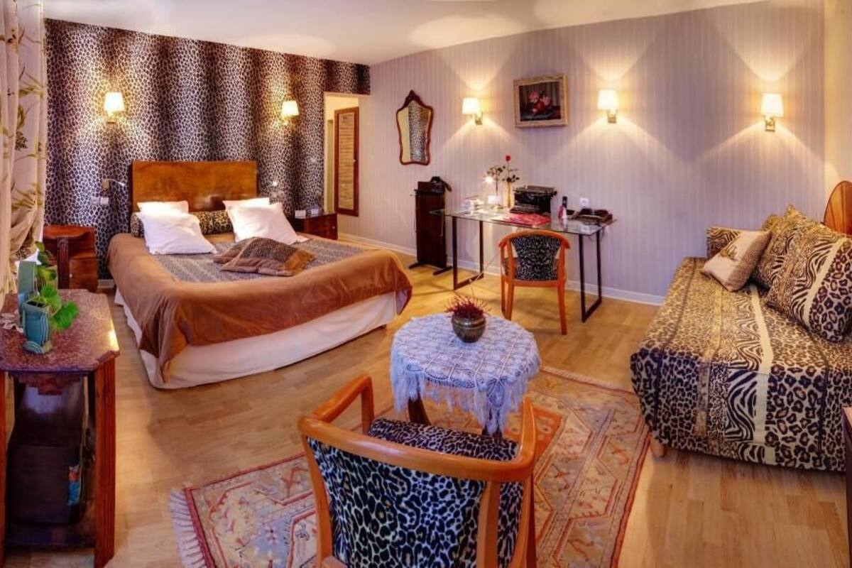 A bedroom with two beds, a desk, a chair, and a small table.