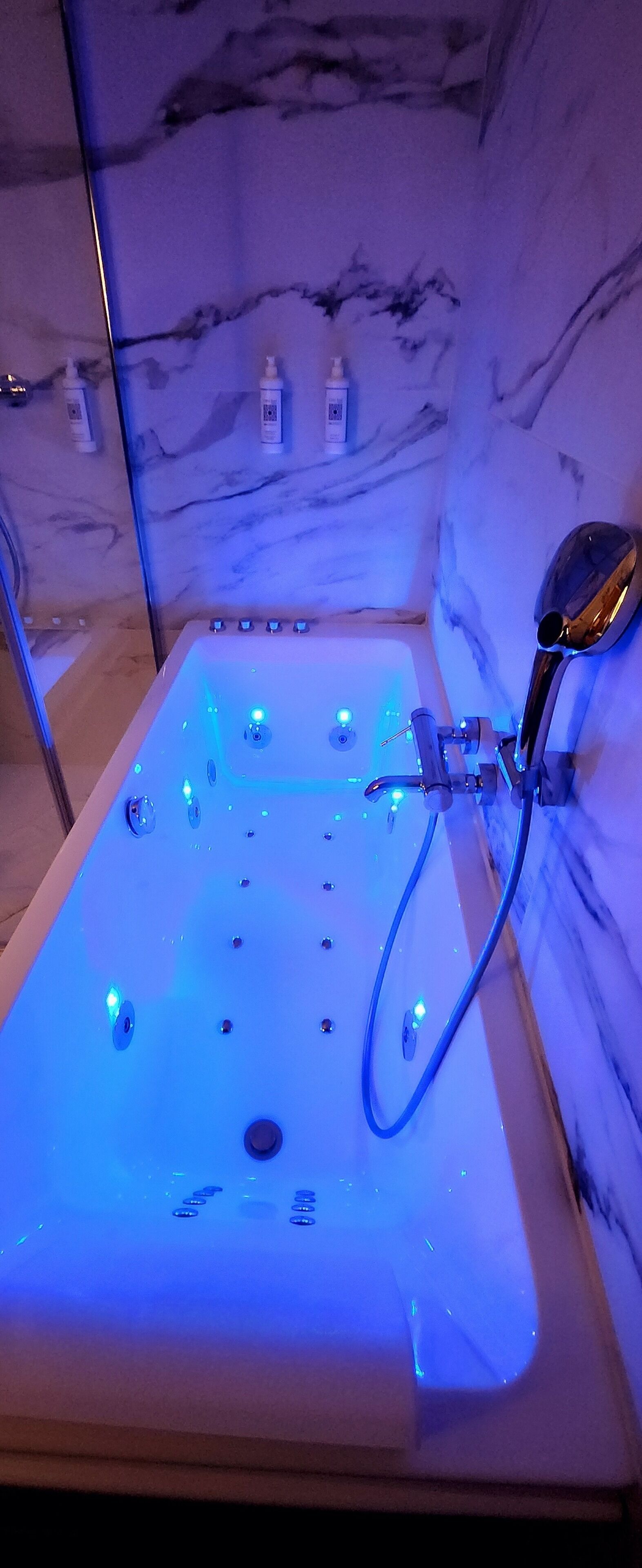 Una bañera de hidromasaje con pared de mármol y ducha.