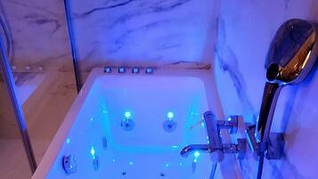 Una bañera de hidromasaje con pared de mármol y ducha.