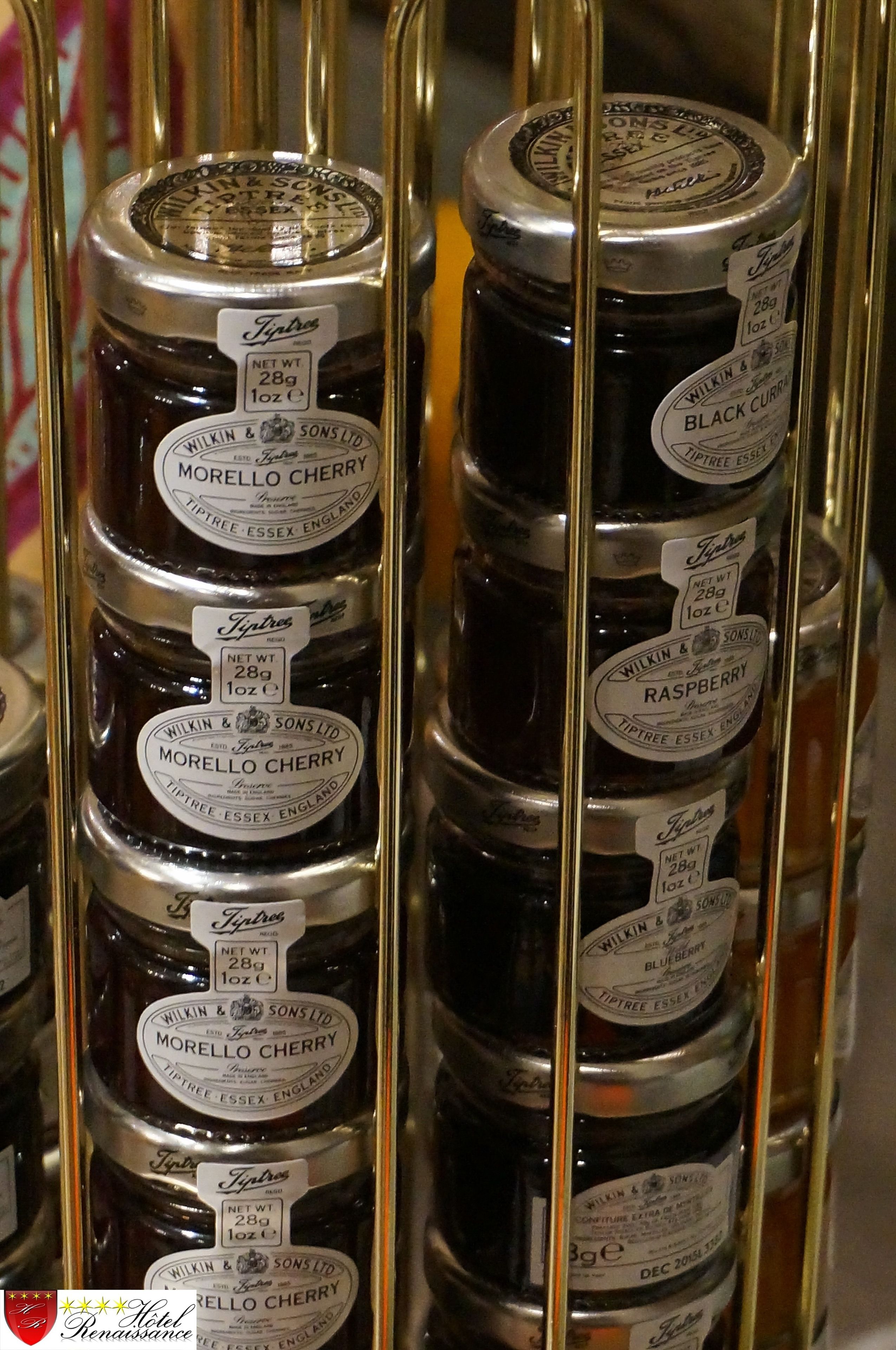 A display of Wilkin & Sons Ltd. Morello Cherry and Raspberry preserves in a glass case.