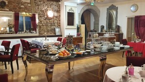 A dining area with tables set for breakfast, including fruits and pastries.