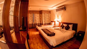 A hotel room with a wooden bed, a TV, a bedside table with a lamp, and a wooden wardrobe. - Danang Pacific Hotel (Da Nang)
