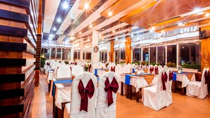 A banquet hall with rows of tables and chairs, wooden paneling on the walls, and large windows. - Danang Pacific Hotel (Da Nang)