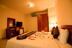 Une chambre d’hôtel équipée d’un lit, d’un bureau, d’une télévision et d’une armoire.