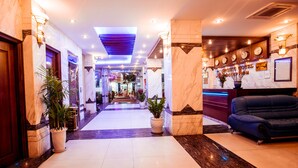A hotel lobby with marble flooring, potted plants, a reception desk, and a blue sofa. - Danang Pacific Hotel (Da Nang)