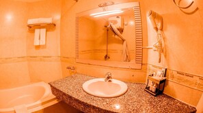 A bathroom with a granite countertop sink, a mirror, a hairdryer, and a bathtub. - Danang Pacific Hotel (Da Nang)