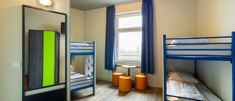 Une chambre avec des lits superposés, un miroir, une petite table et une fenêtre avec des rideaux.