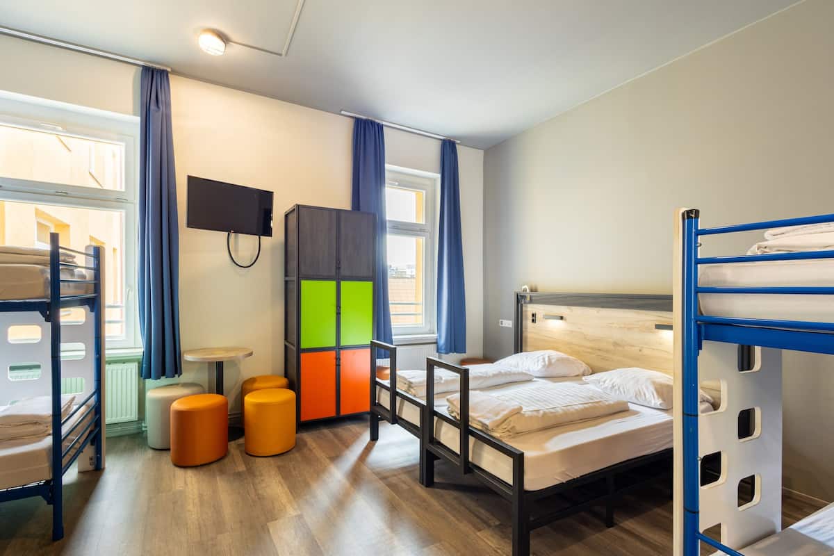 Une chambre de dortoir équipée de lits superposés, d’une télévision, d’un bureau et d’une armoire aux couleurs vives.