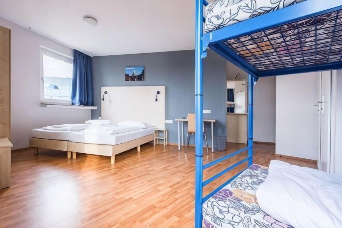 Une chambre avec deux lits, un bureau, une chaise, une armoire et une fenêtre.