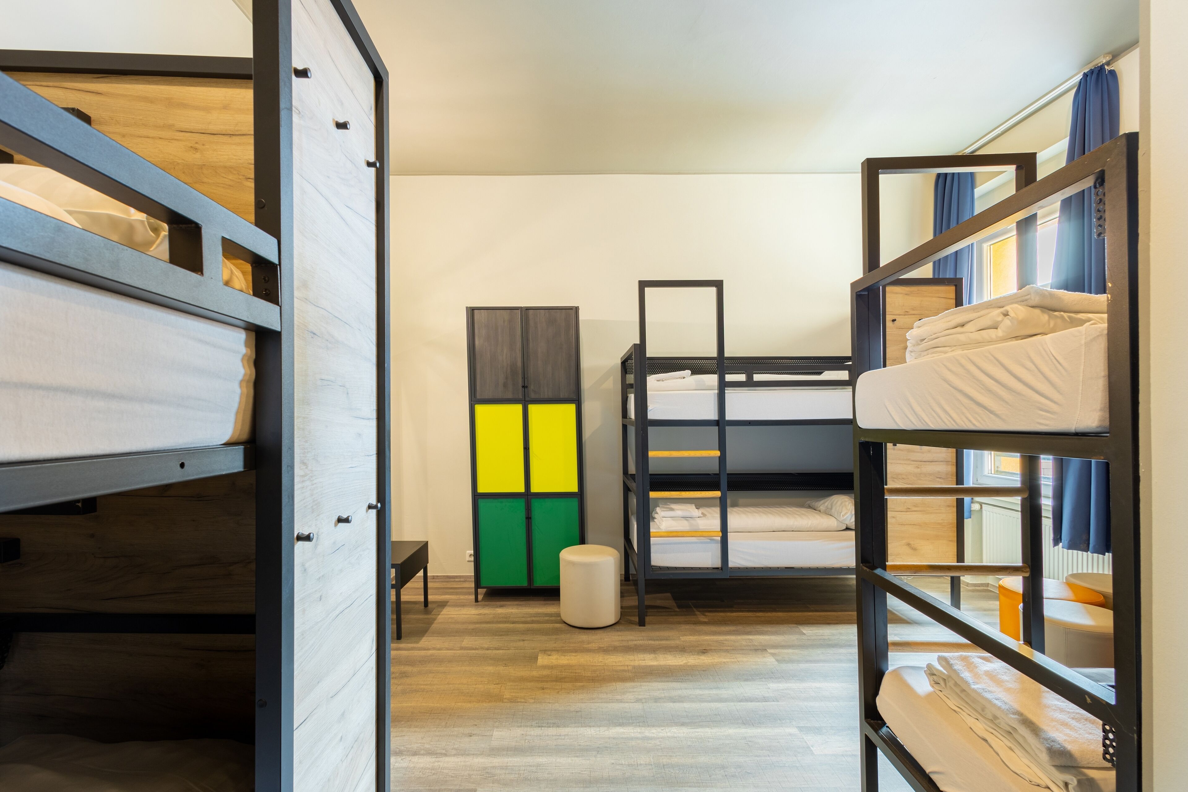 Habitació compacta amb lliteres, una taula petita i un armari amb una porta de colors.