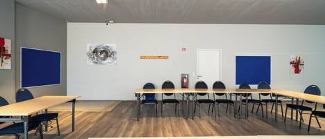 Una sala de conferencias con una larga mesa, sillas, una pizarra y un extintor.