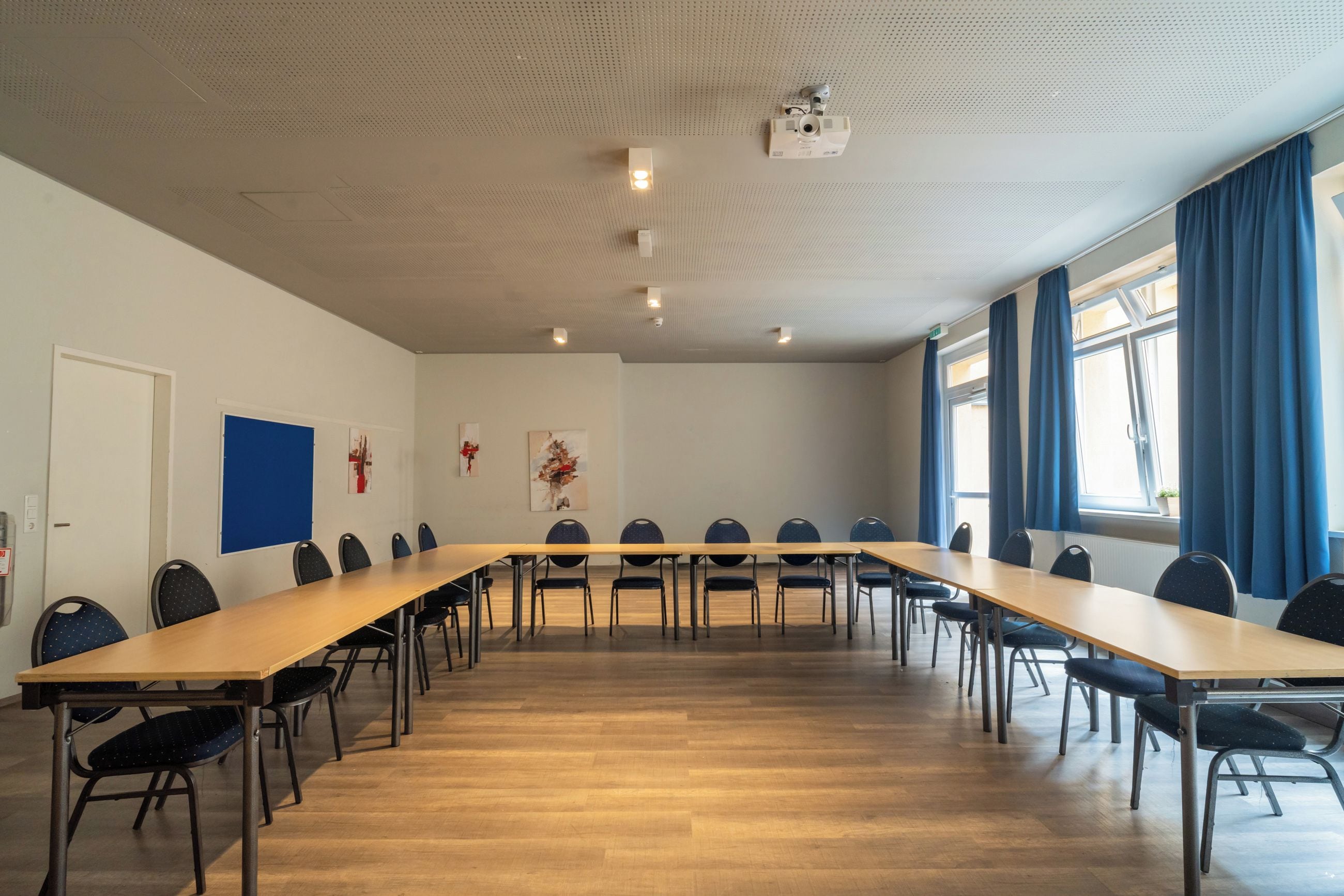 A conference room with a long table and chairs, a projector, and artwork on the walls.