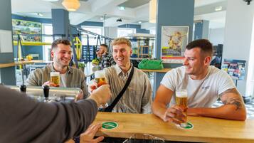 Eine Gruppe von Personen, die mit Bier anstoßen, in einer Bar mit einer Holztresen und Untersetzer.