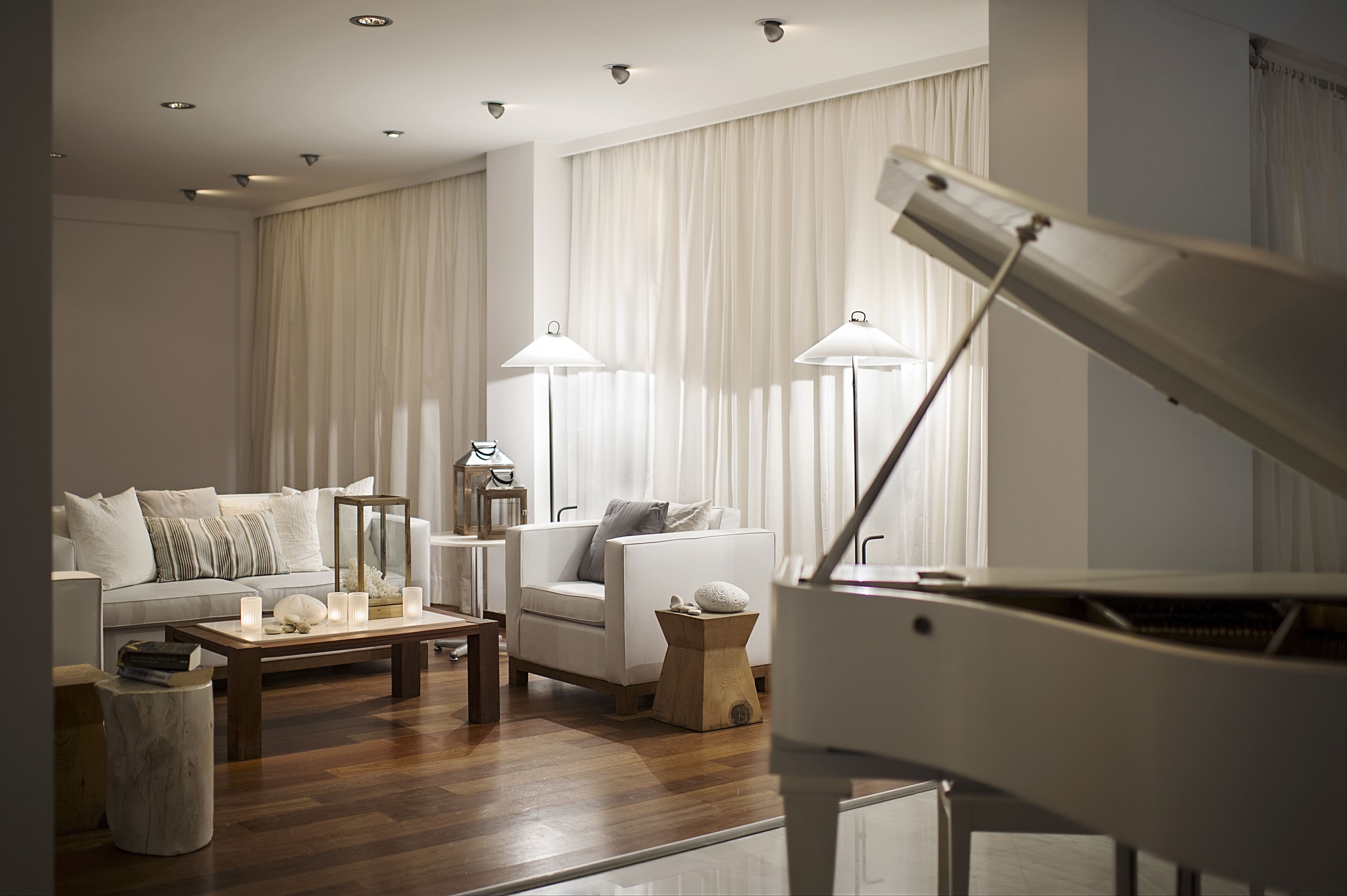 A modern living room with a piano, a sofa, a coffee table, and two floor lamps.